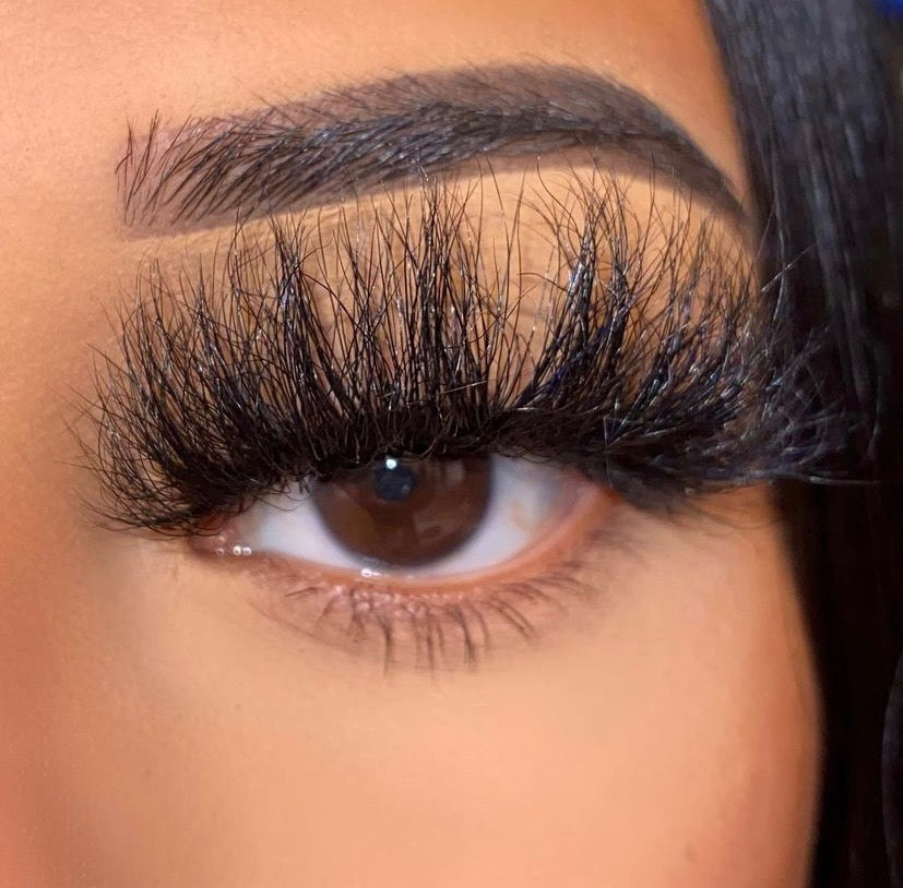 A close-up of a brown eye with IT gurl Fluffy Mink Lash Strip lashes and a sharply defined brow. The smooth skin and precise makeup application create a naturally voluminous look.