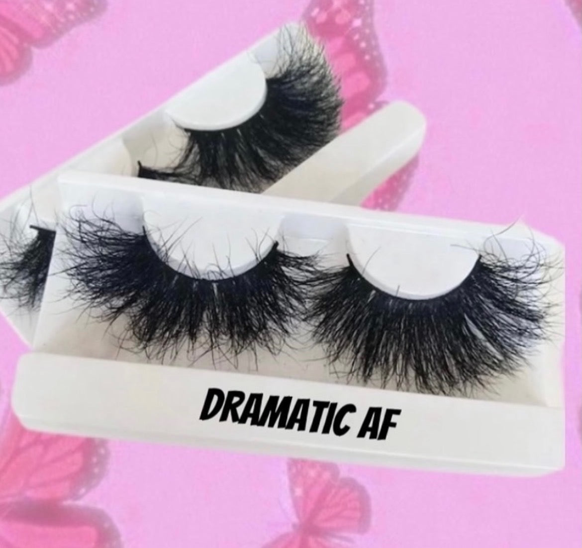 Lash Style Dramatic AF features thick, dramatic lashes in a white case with its label, shown on a pink background with butterfly designs for voluminous eye enhancement.